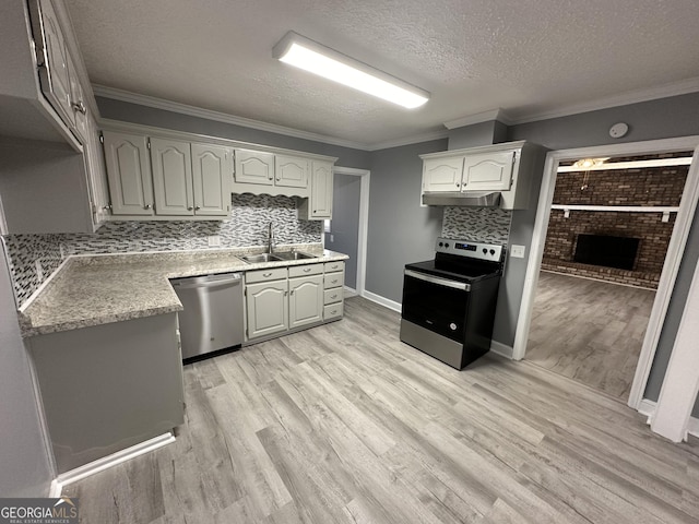 kitchen with appliances with stainless steel finishes, backsplash, a textured ceiling, sink, and a fireplace