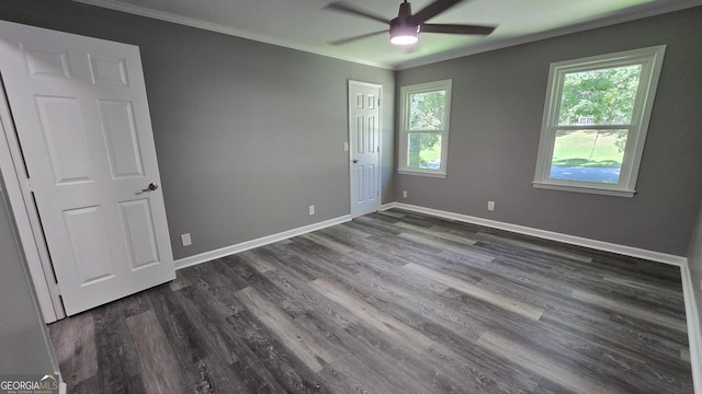 unfurnished bedroom featuring a ceiling fan, baseboards, dark wood-type flooring, and crown molding