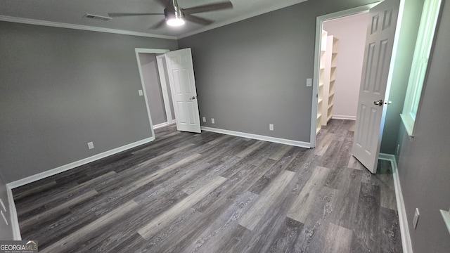 unfurnished bedroom featuring a ceiling fan, baseboards, visible vents, dark wood-style floors, and crown molding