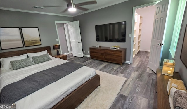 bedroom featuring baseboards, visible vents, wood finished floors, and ornamental molding