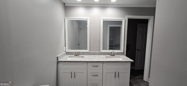 bathroom with ornamental molding, double vanity, a sink, and walk in shower