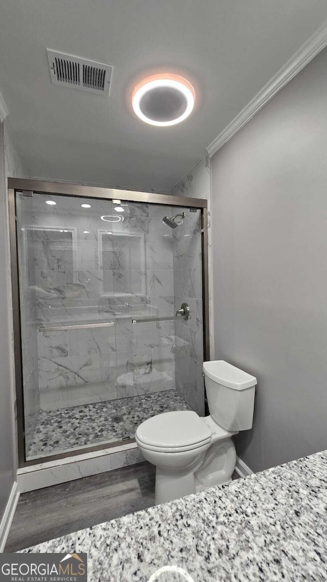 full bathroom with a marble finish shower, visible vents, toilet, wood finished floors, and crown molding