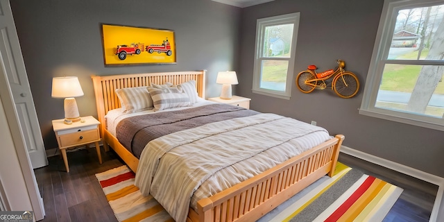 bedroom with multiple windows, baseboards, and wood finished floors