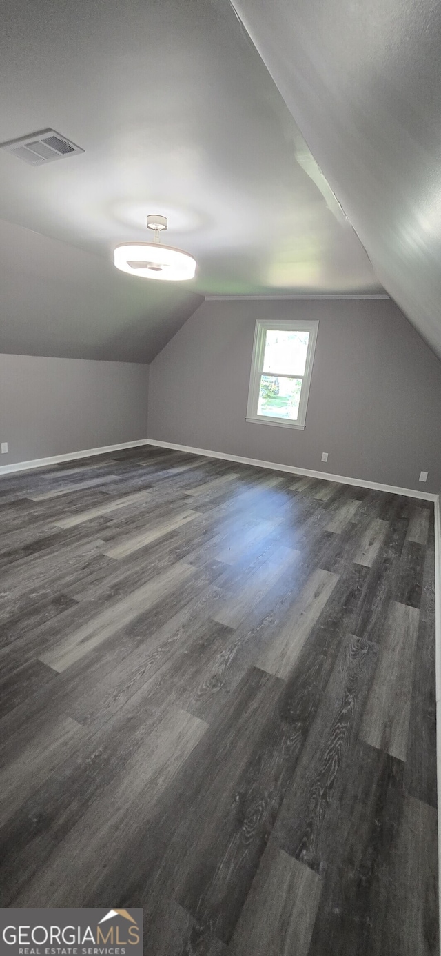 bonus room featuring baseboards, visible vents, vaulted ceiling, and dark wood-style flooring