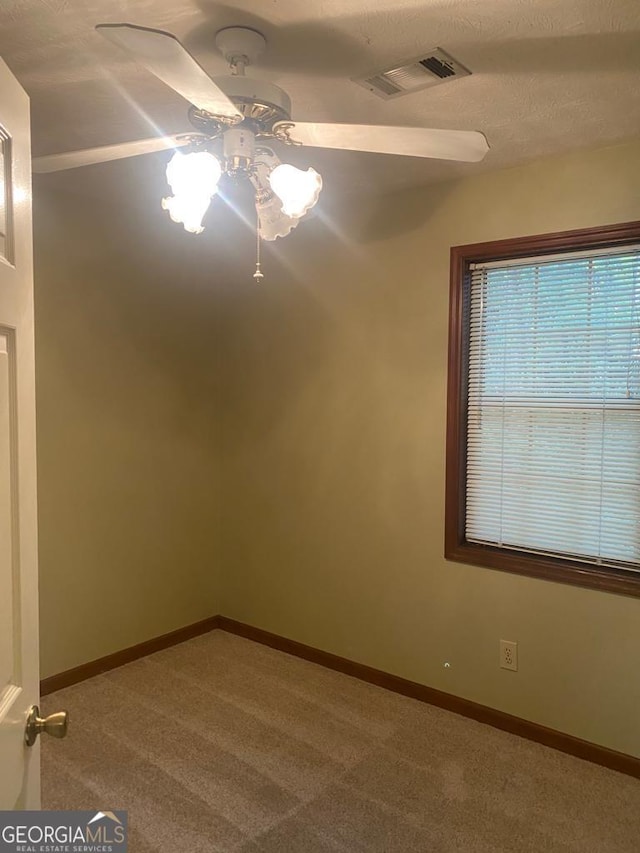 carpeted spare room featuring ceiling fan and a textured ceiling