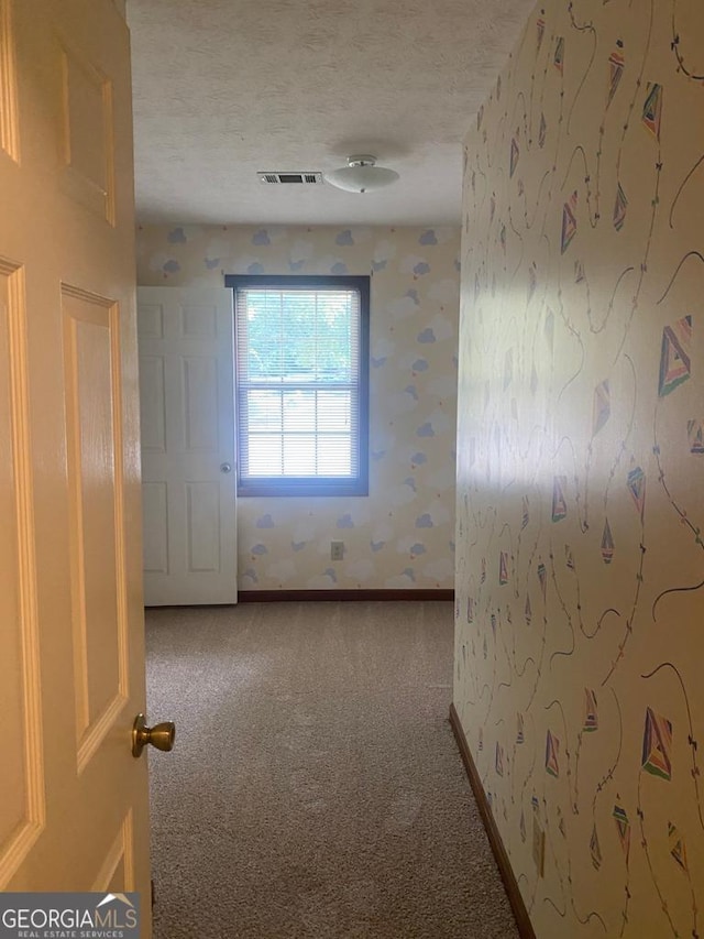 carpeted empty room with a textured ceiling