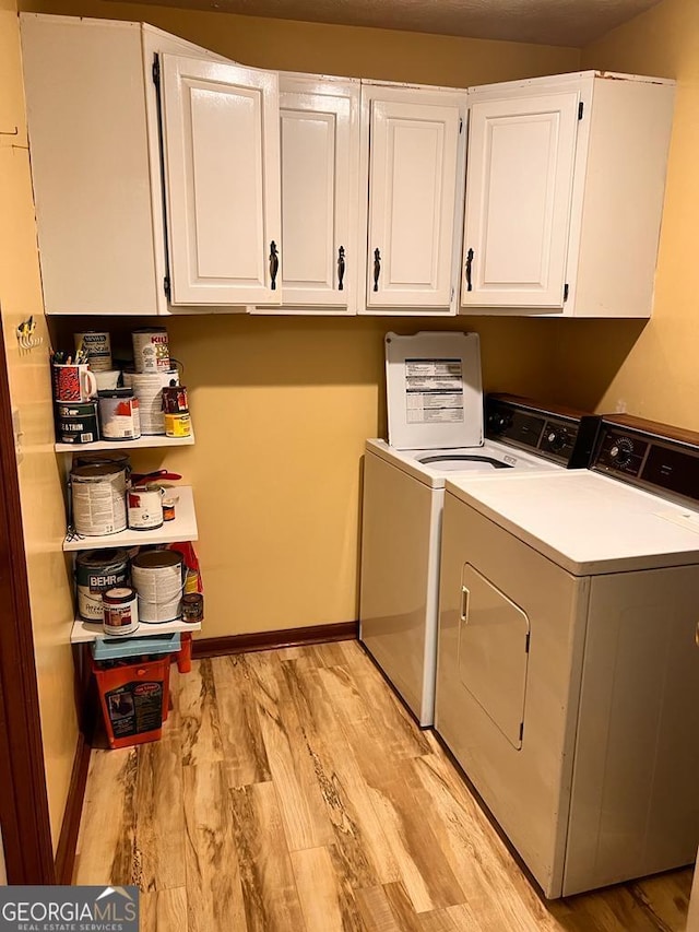 washroom with cabinets, washer and dryer, and light hardwood / wood-style flooring