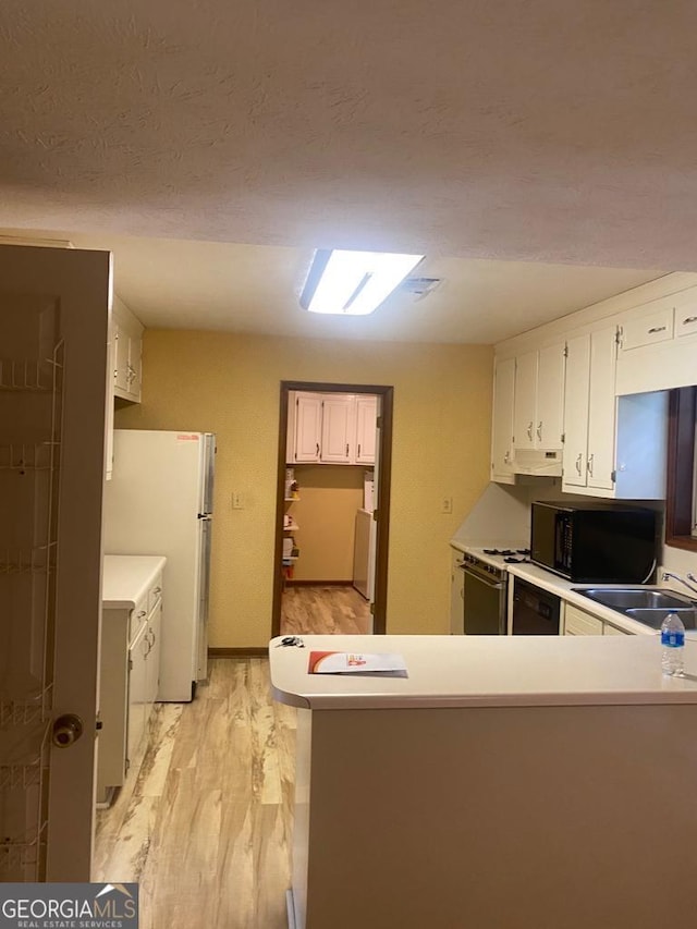 kitchen featuring washer and dryer, black appliances, white cabinetry, kitchen peninsula, and light hardwood / wood-style flooring