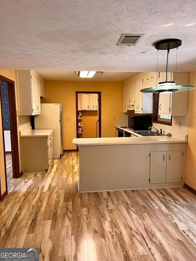 kitchen with sink, kitchen peninsula, light hardwood / wood-style floors, and decorative light fixtures