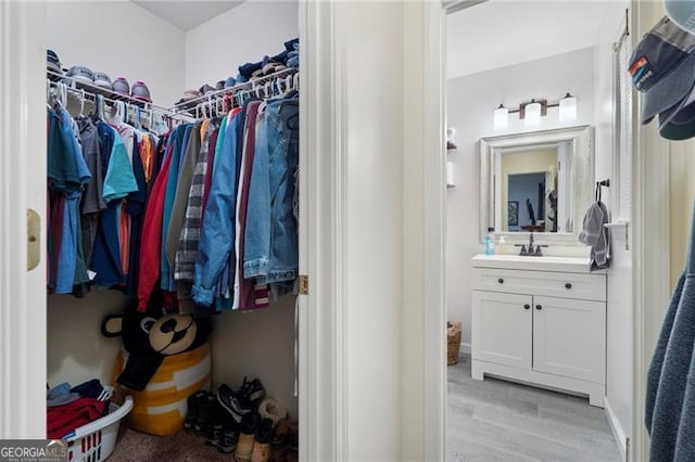 walk in closet featuring light hardwood / wood-style flooring and sink