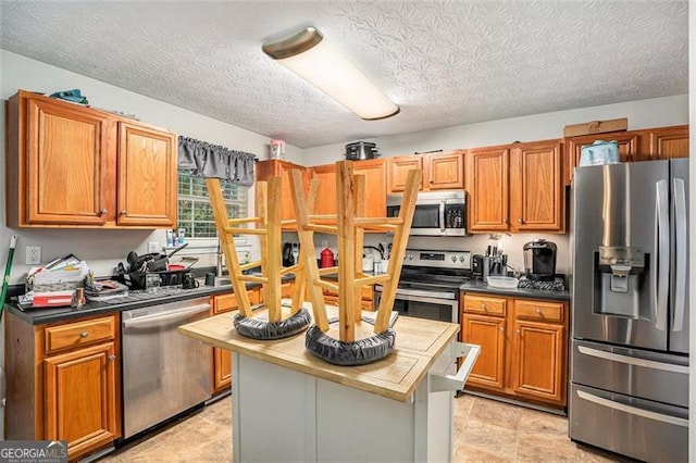 kitchen featuring a center island, a textured ceiling, and appliances with stainless steel finishes