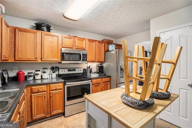 kitchen featuring a textured ceiling, stainless steel appliances, and sink