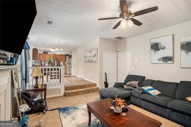 carpeted living room featuring ceiling fan with notable chandelier and a textured ceiling