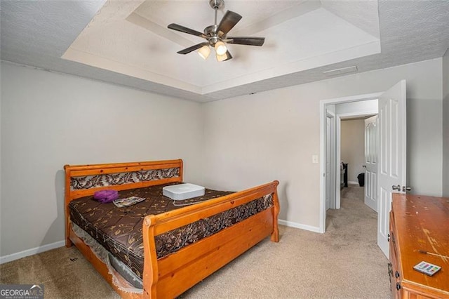 carpeted bedroom featuring a raised ceiling, ceiling fan, and a textured ceiling