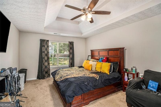 bedroom featuring light carpet, a textured ceiling, a raised ceiling, and ceiling fan