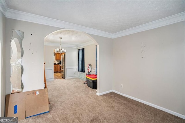 empty room featuring light carpet, a notable chandelier, and ornamental molding