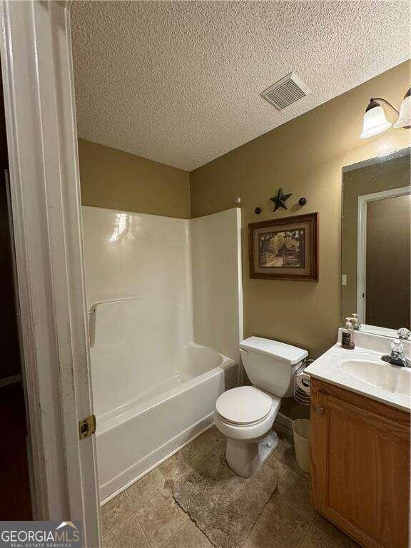 full bathroom with vanity, toilet, a textured ceiling, and bathing tub / shower combination