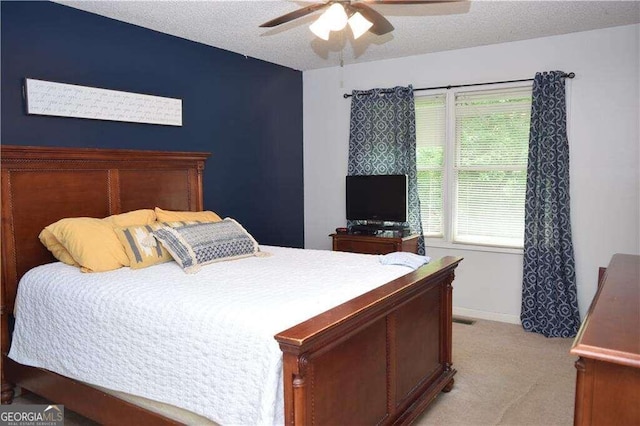 carpeted bedroom featuring multiple windows, a textured ceiling, and ceiling fan