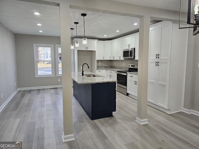 kitchen with a kitchen island with sink, white cabinetry, sink, and appliances with stainless steel finishes