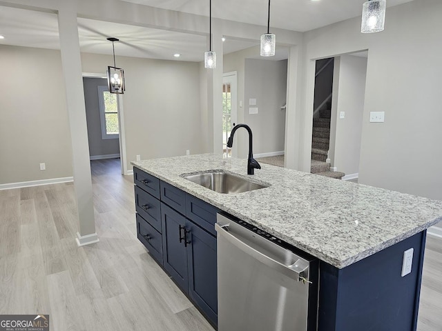 kitchen with light stone countertops, stainless steel dishwasher, sink, pendant lighting, and a center island with sink