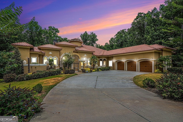 mediterranean / spanish-style home featuring a yard and a garage