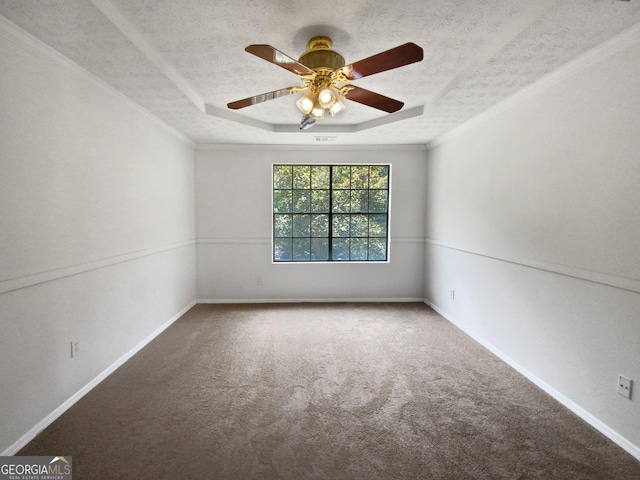 carpeted spare room with ceiling fan, ornamental molding, a textured ceiling, and a tray ceiling