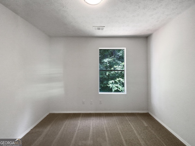 unfurnished room featuring carpet and a textured ceiling