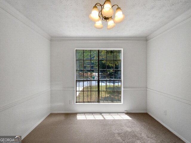 spare room with carpet, a textured ceiling, crown molding, and a chandelier