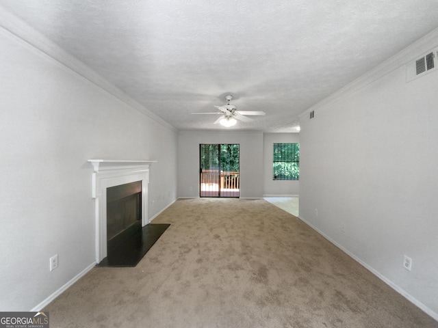 unfurnished living room featuring ceiling fan, carpet, a textured ceiling, and ornamental molding