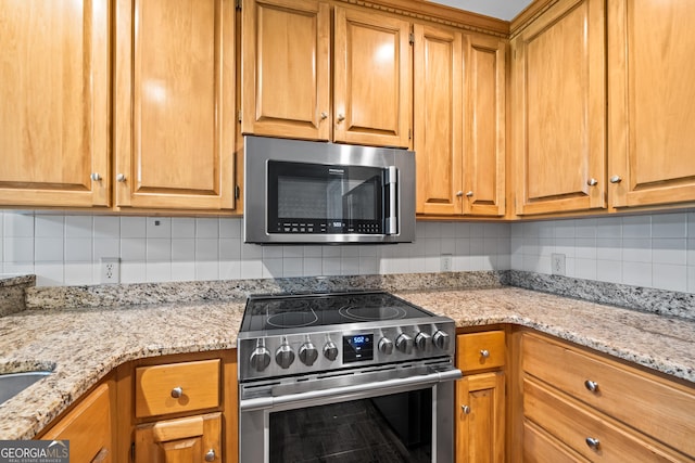 kitchen featuring backsplash, light stone counters, and stainless steel appliances