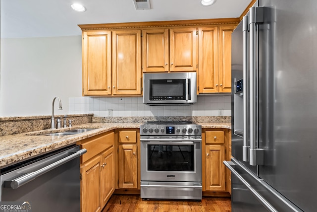 kitchen featuring light stone countertops, sink, premium appliances, tasteful backsplash, and dark hardwood / wood-style floors