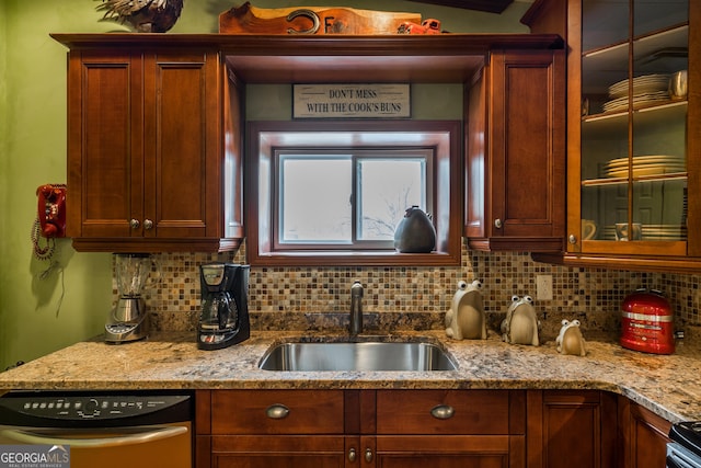 kitchen with backsplash, light stone countertops, sink, and appliances with stainless steel finishes