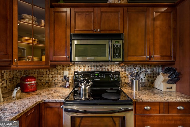 kitchen featuring light stone countertops, black range with electric stovetop, and tasteful backsplash