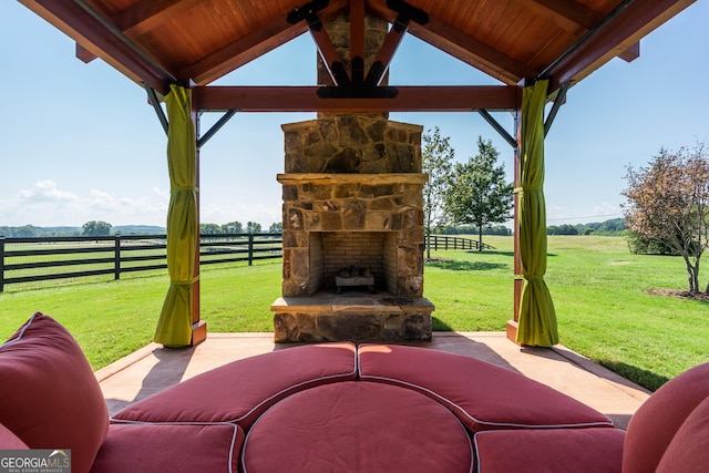 view of patio / terrace with an outdoor stone fireplace, a rural view, and a gazebo