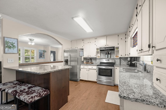 kitchen with sink, light stone countertops, white cabinetry, kitchen peninsula, and stainless steel appliances