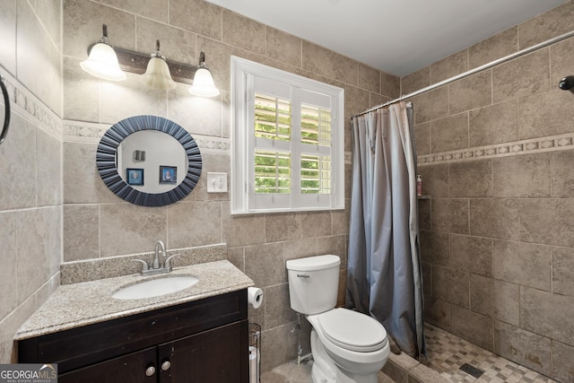 bathroom with curtained shower, vanity, tile walls, and toilet