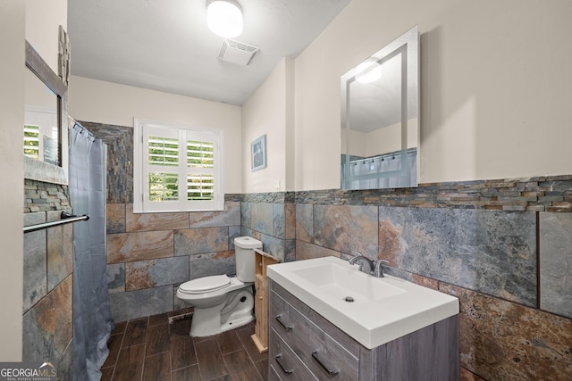 bathroom with walk in shower, vanity, toilet, and tile walls