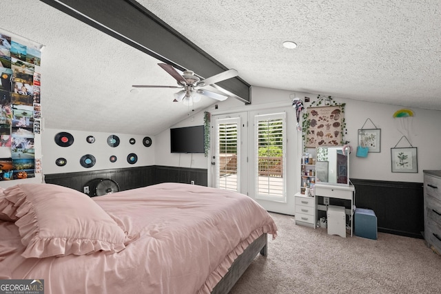 carpeted bedroom with access to exterior, ceiling fan, wooden walls, and a textured ceiling