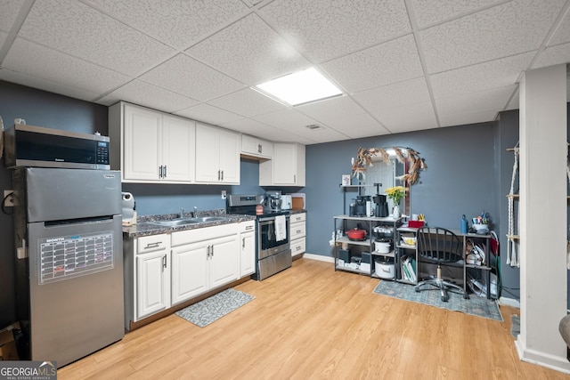 kitchen featuring stainless steel electric stove, white cabinetry, sink, and light hardwood / wood-style floors