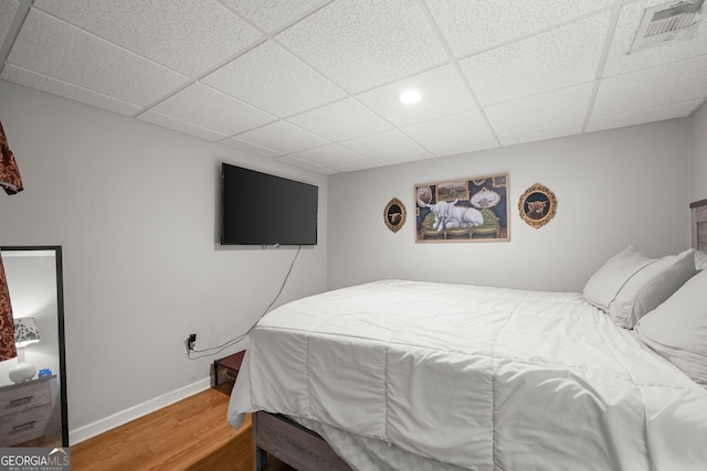 bedroom featuring wood-type flooring and a drop ceiling