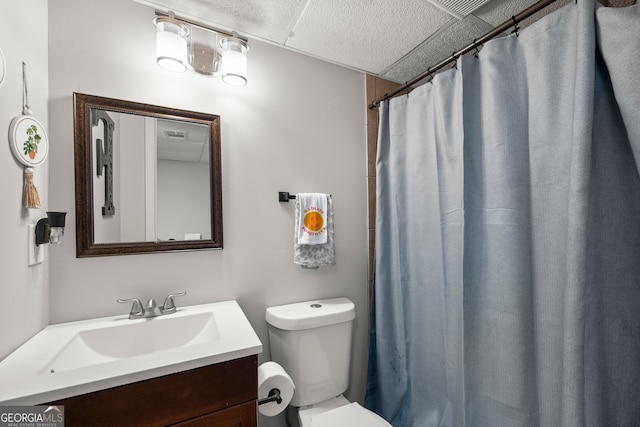 bathroom with a shower with curtain, a drop ceiling, vanity, and toilet