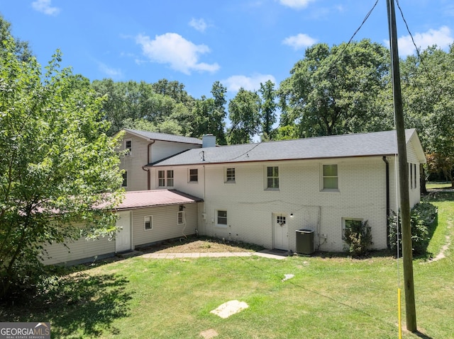 rear view of property featuring a yard and cooling unit