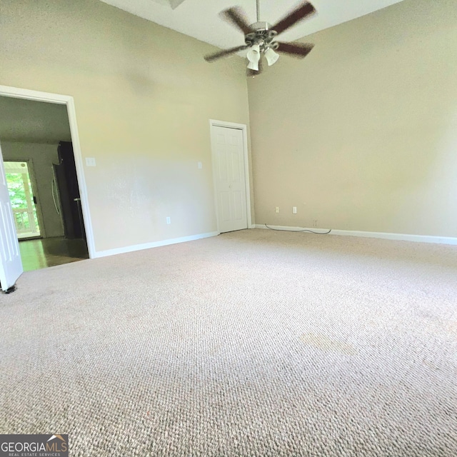 carpeted empty room with a high ceiling and ceiling fan