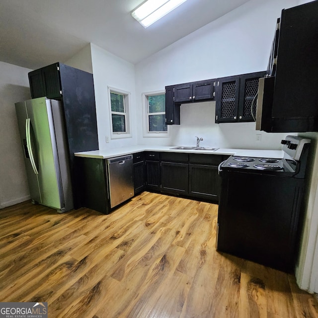 kitchen featuring appliances with stainless steel finishes, light hardwood / wood-style floors, sink, and vaulted ceiling