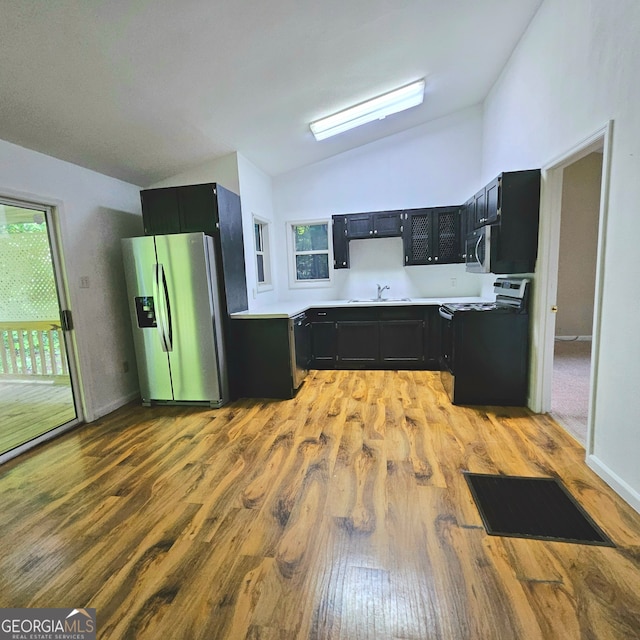 kitchen featuring stainless steel appliances, vaulted ceiling, sink, and hardwood / wood-style flooring