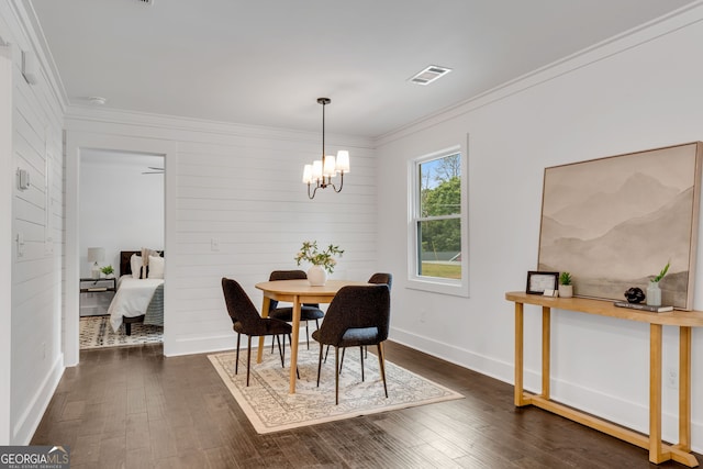 dining area with crown molding, dark wood-type flooring, and an inviting chandelier