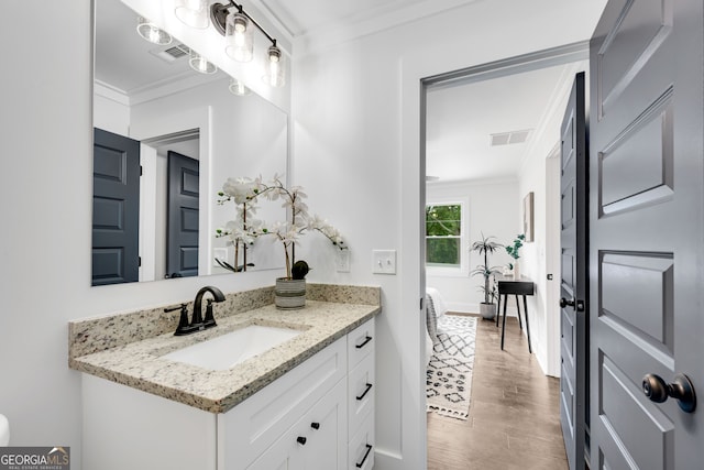 bathroom featuring vanity, wood-type flooring, and ornamental molding