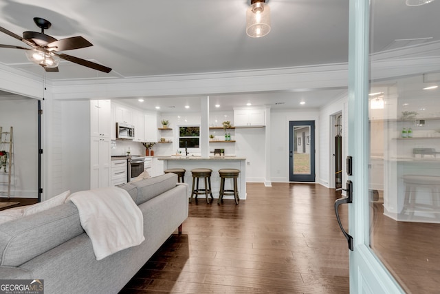 living room with ceiling fan, dark hardwood / wood-style flooring, and ornamental molding