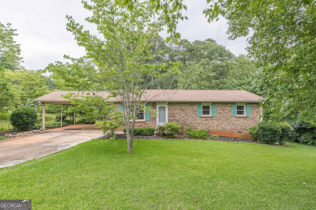 ranch-style home featuring a carport and a front lawn