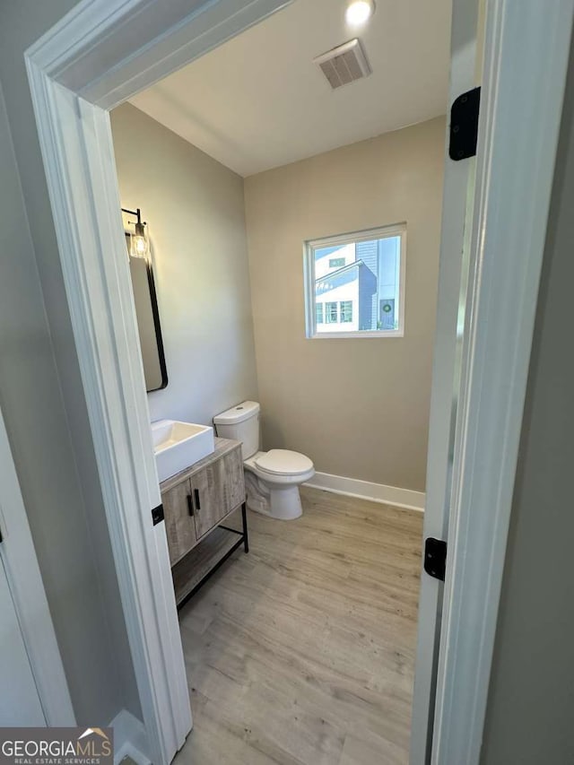 bathroom with hardwood / wood-style flooring, vanity, and toilet